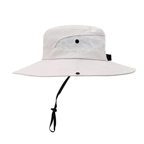 AEFSHAN beige bucket hat with a wide brim and a back ponytail hole, sitting on a travel journal.